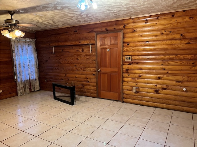 tiled foyer entrance with a textured ceiling, ceiling fan, and rustic walls