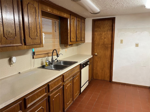 kitchen with white dishwasher, dark tile patterned flooring, sink, and a textured ceiling