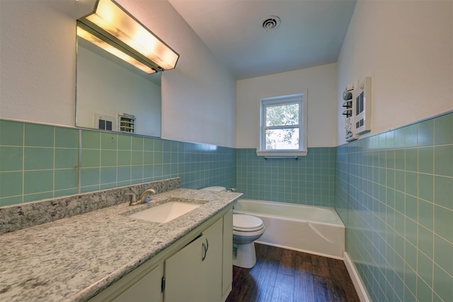 full bathroom with vanity, toilet, hardwood / wood-style floors, and tile walls