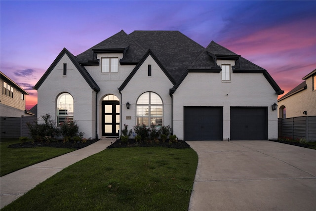 french country inspired facade with a yard and a garage