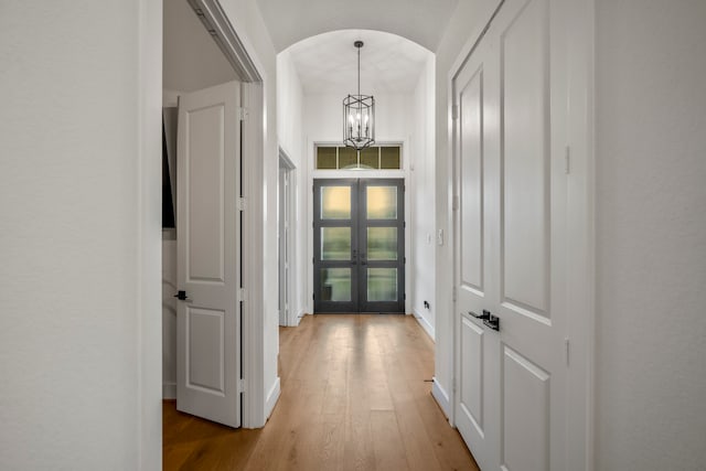 interior space with french doors, light hardwood / wood-style floors, and an inviting chandelier