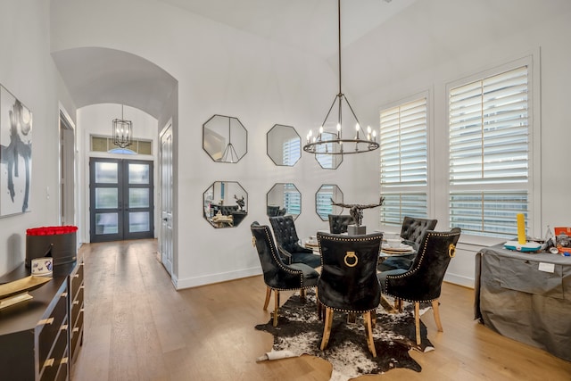 dining room featuring french doors, light hardwood / wood-style floors, an inviting chandelier, and plenty of natural light