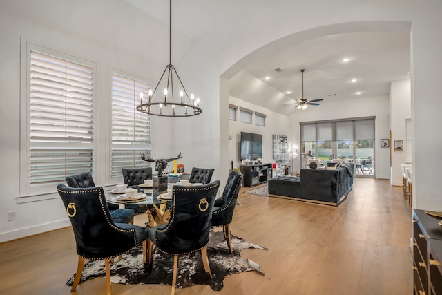 dining space with a healthy amount of sunlight, wood-type flooring, and ceiling fan with notable chandelier