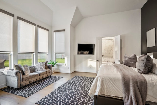 bedroom with vaulted ceiling, light hardwood / wood-style flooring, and ensuite bath