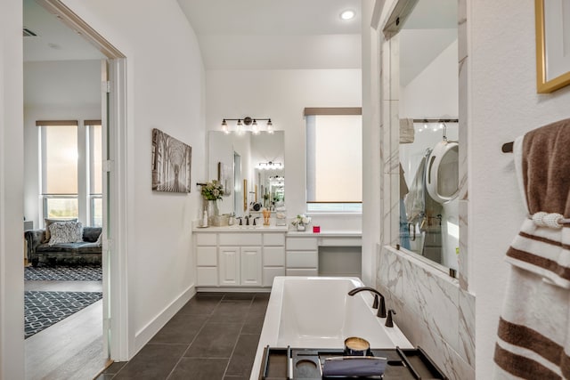 bathroom featuring vanity, lofted ceiling, a tub to relax in, and tile patterned floors