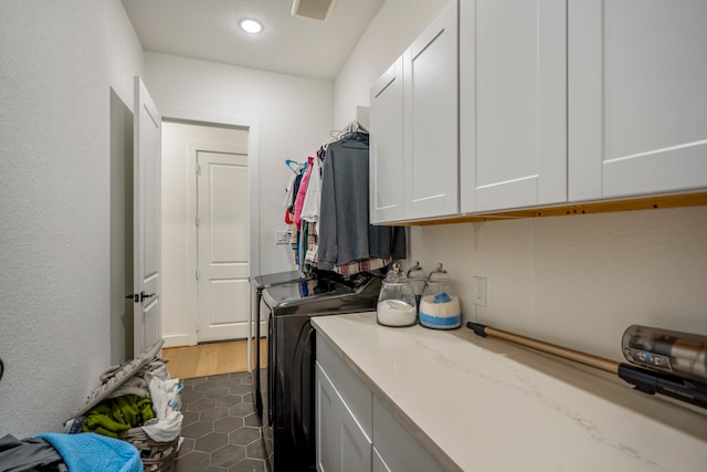 clothes washing area featuring cabinets, dark hardwood / wood-style floors, and washing machine and clothes dryer