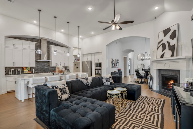 living room with light hardwood / wood-style flooring, a tiled fireplace, and ceiling fan