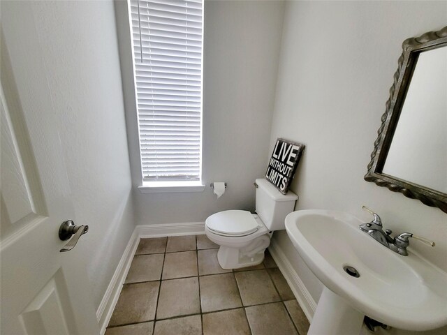 bathroom with toilet, sink, and tile patterned floors