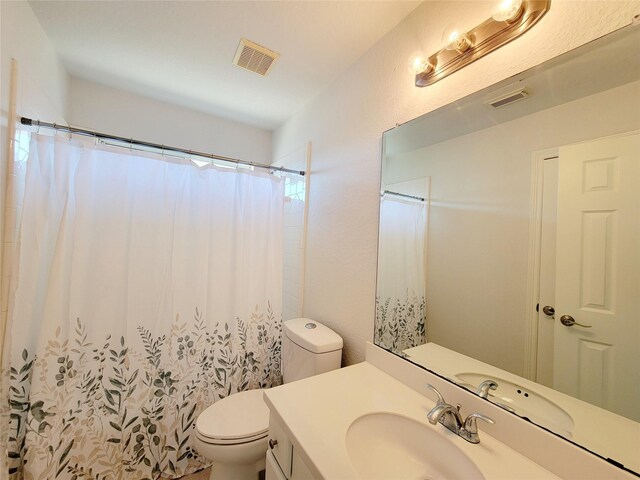 bathroom featuring toilet, vanity, and a shower with shower curtain