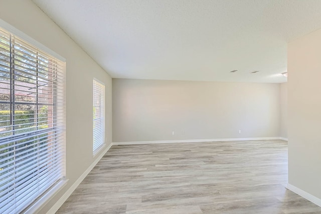 spare room with a textured ceiling and light hardwood / wood-style floors