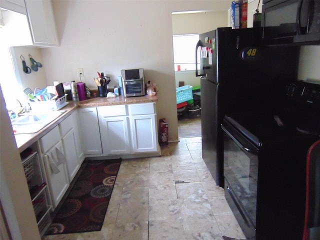 kitchen featuring white cabinetry, black appliances, light countertops, and a sink