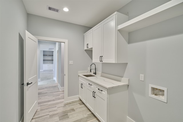 laundry area featuring washer hookup, light hardwood / wood-style floors, cabinets, and sink