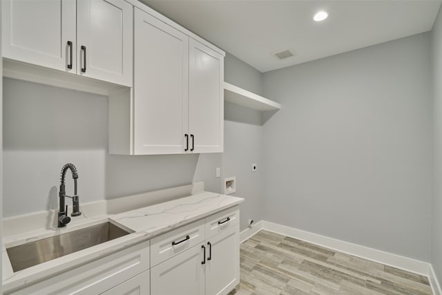 laundry area featuring cabinets, electric dryer hookup, hookup for a washing machine, light hardwood / wood-style flooring, and sink