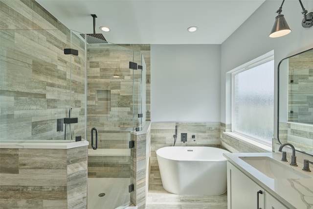 bathroom featuring vanity, tile walls, and plus walk in shower