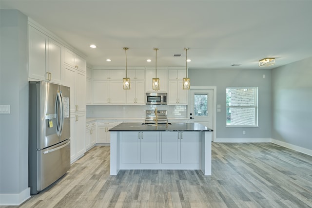 kitchen with an island with sink, stainless steel appliances, white cabinetry, and light hardwood / wood-style floors