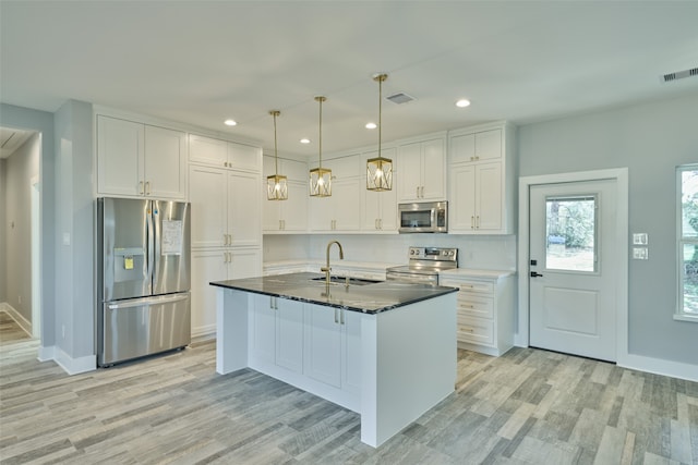 kitchen featuring light hardwood / wood-style flooring, a kitchen island with sink, stainless steel appliances, sink, and white cabinetry