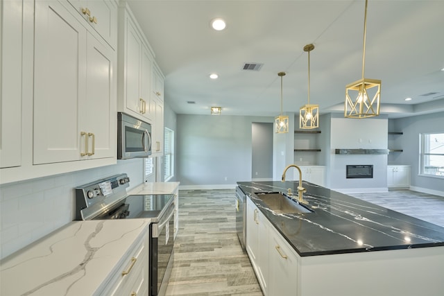 kitchen with appliances with stainless steel finishes, light hardwood / wood-style floors, white cabinetry, and sink