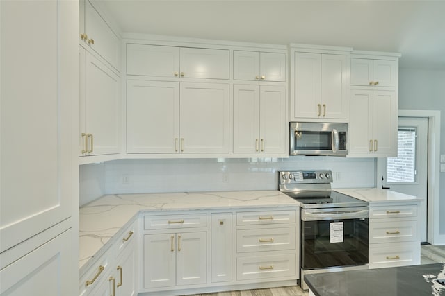 kitchen featuring light stone counters, light wood-type flooring, appliances with stainless steel finishes, and white cabinets