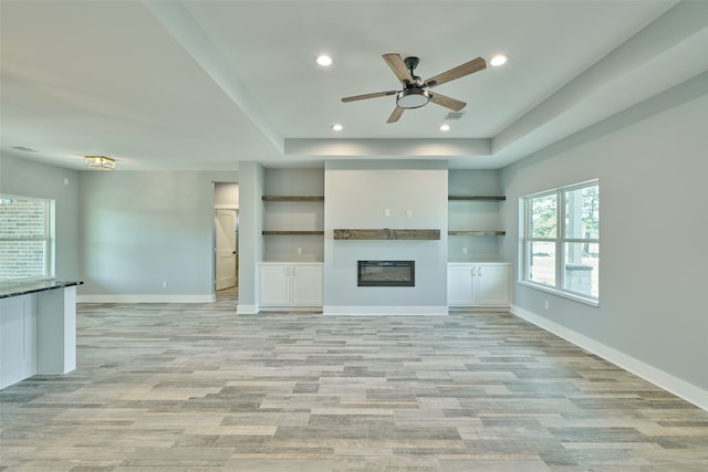 unfurnished living room featuring light wood-type flooring, built in shelves, and ceiling fan