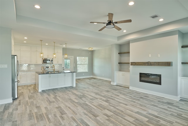 kitchen featuring light wood-type flooring, white cabinetry, stainless steel appliances, sink, and ceiling fan