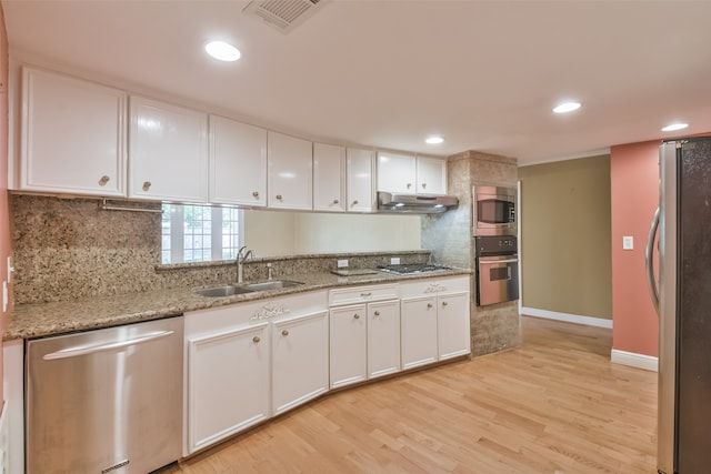 kitchen with appliances with stainless steel finishes, light hardwood / wood-style flooring, white cabinets, and sink