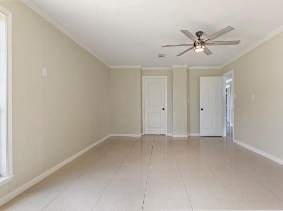 tiled spare room featuring crown molding and ceiling fan