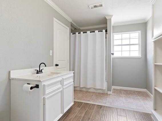 bathroom with vanity, crown molding, wood-type flooring, and walk in shower