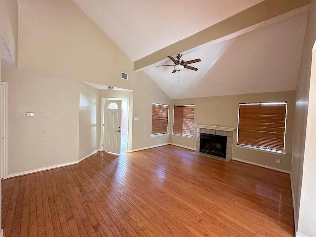 unfurnished living room with a fireplace, light wood-type flooring, high vaulted ceiling, ceiling fan, and beam ceiling