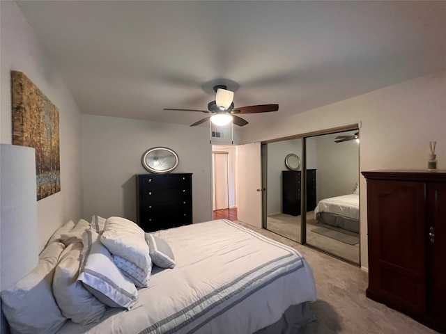 bedroom with a closet, ceiling fan, and light colored carpet