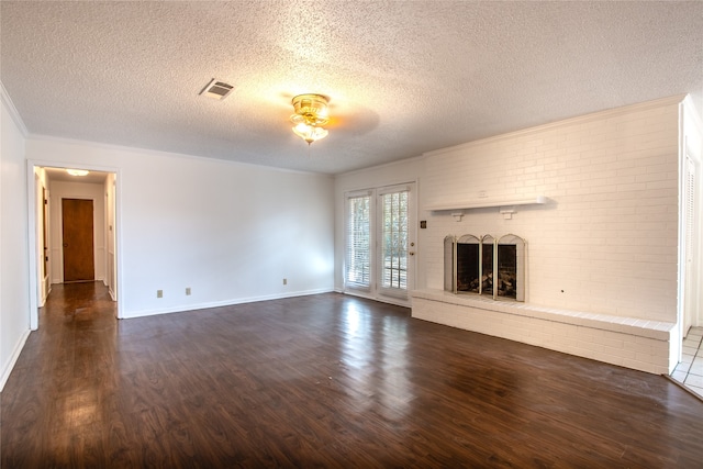 unfurnished living room featuring dark wood-type flooring, a textured ceiling, and a brick fireplace