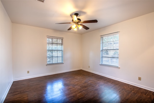 empty room featuring dark wood-type flooring, ceiling fan, and a wealth of natural light