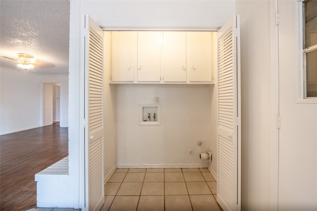 washroom featuring hookup for a washing machine, light hardwood / wood-style flooring, cabinets, and a textured ceiling