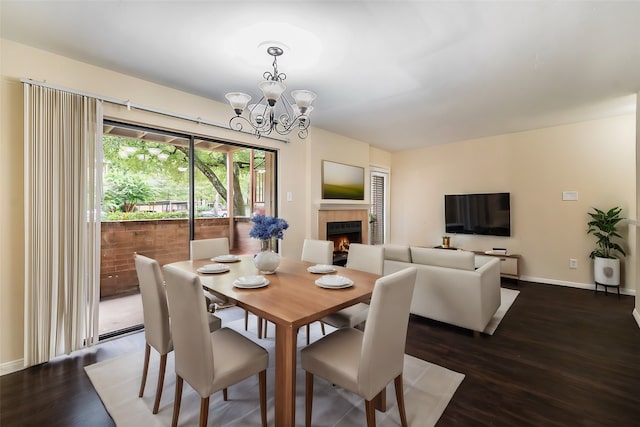 dining area featuring a notable chandelier, dark hardwood / wood-style floors, and a tile fireplace