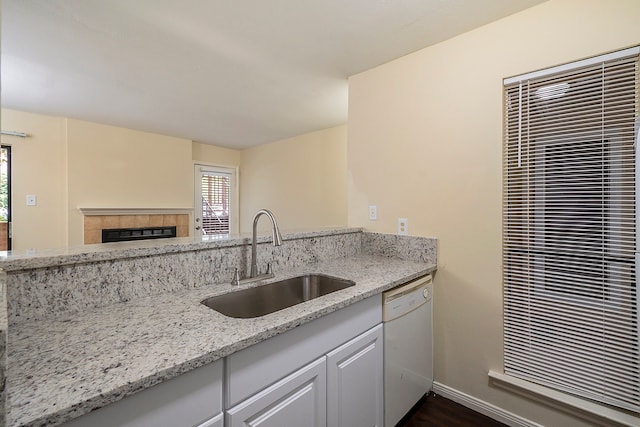 kitchen with dishwasher, sink, a healthy amount of sunlight, and light stone counters