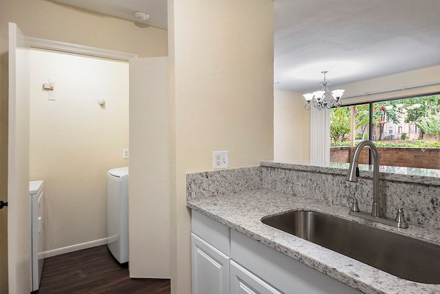 kitchen featuring light stone countertops, sink, dark hardwood / wood-style floors, a notable chandelier, and independent washer and dryer