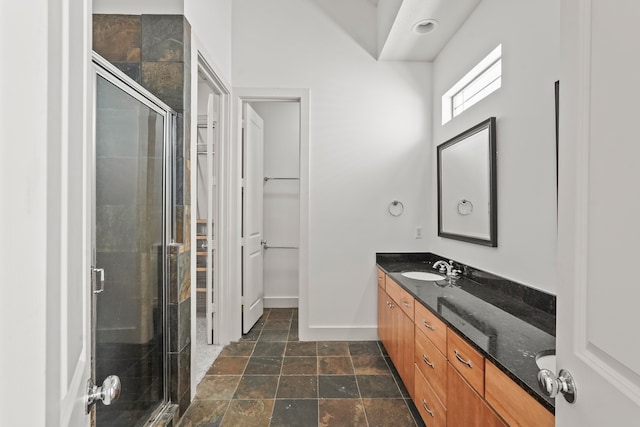 bathroom featuring a shower with door and vanity