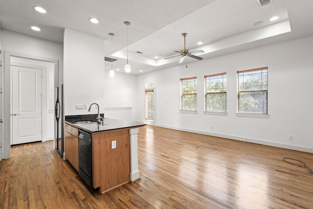 kitchen with a center island with sink, a raised ceiling, sink, and hardwood / wood-style flooring