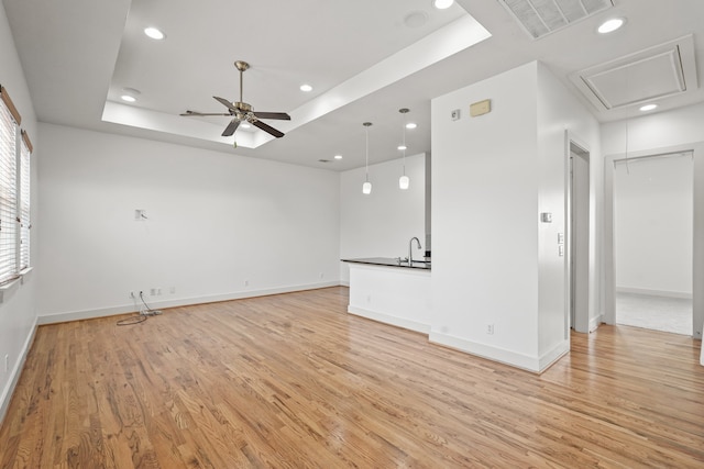 spare room featuring ceiling fan, a raised ceiling, sink, and light hardwood / wood-style flooring