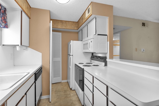 kitchen with white cabinets, light tile patterned floors, white appliances, sink, and a textured ceiling