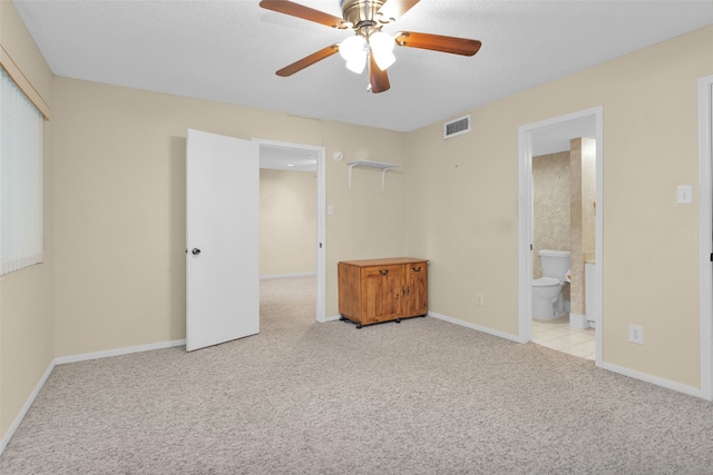 unfurnished bedroom with light colored carpet, ceiling fan, a textured ceiling, and ensuite bath