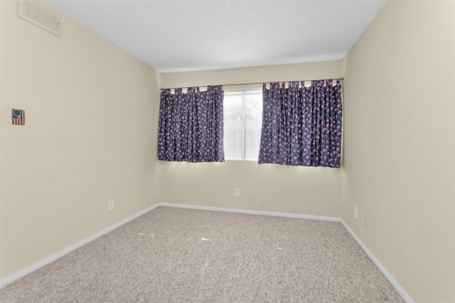 carpeted empty room featuring a textured ceiling