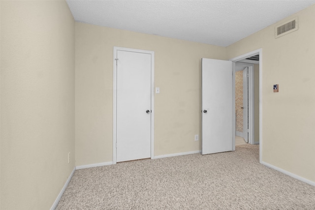 unfurnished bedroom with light colored carpet and a textured ceiling