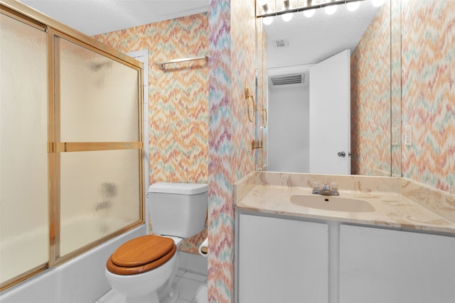 full bathroom with a textured ceiling, vanity, combined bath / shower with glass door, toilet, and tile patterned floors