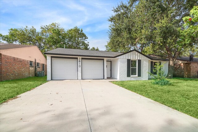 ranch-style home featuring a front lawn, a garage, and central AC unit