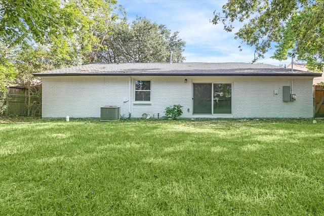 rear view of property featuring central air condition unit and a yard