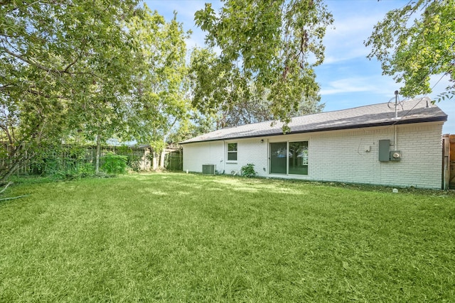 rear view of property with cooling unit and a yard