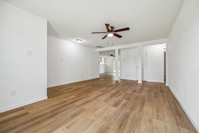 unfurnished bedroom with light wood-type flooring, a textured ceiling, two closets, and ceiling fan