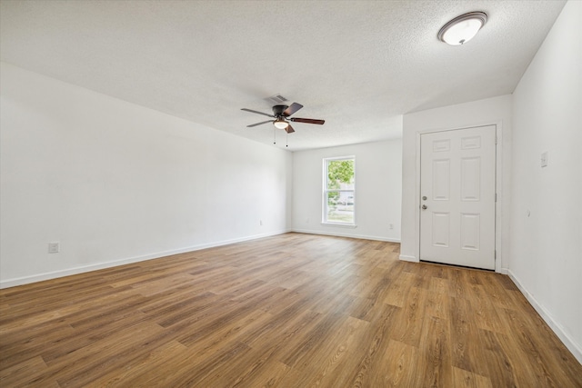 empty room with a textured ceiling, ceiling fan, and hardwood / wood-style flooring