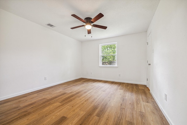 empty room with a textured ceiling, ceiling fan, and light hardwood / wood-style floors