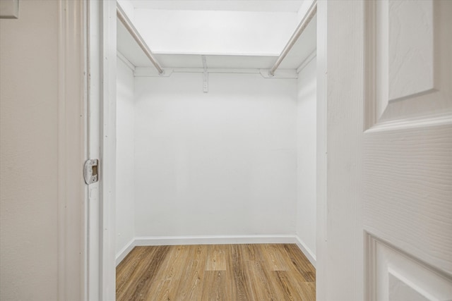 walk in closet with light hardwood / wood-style floors